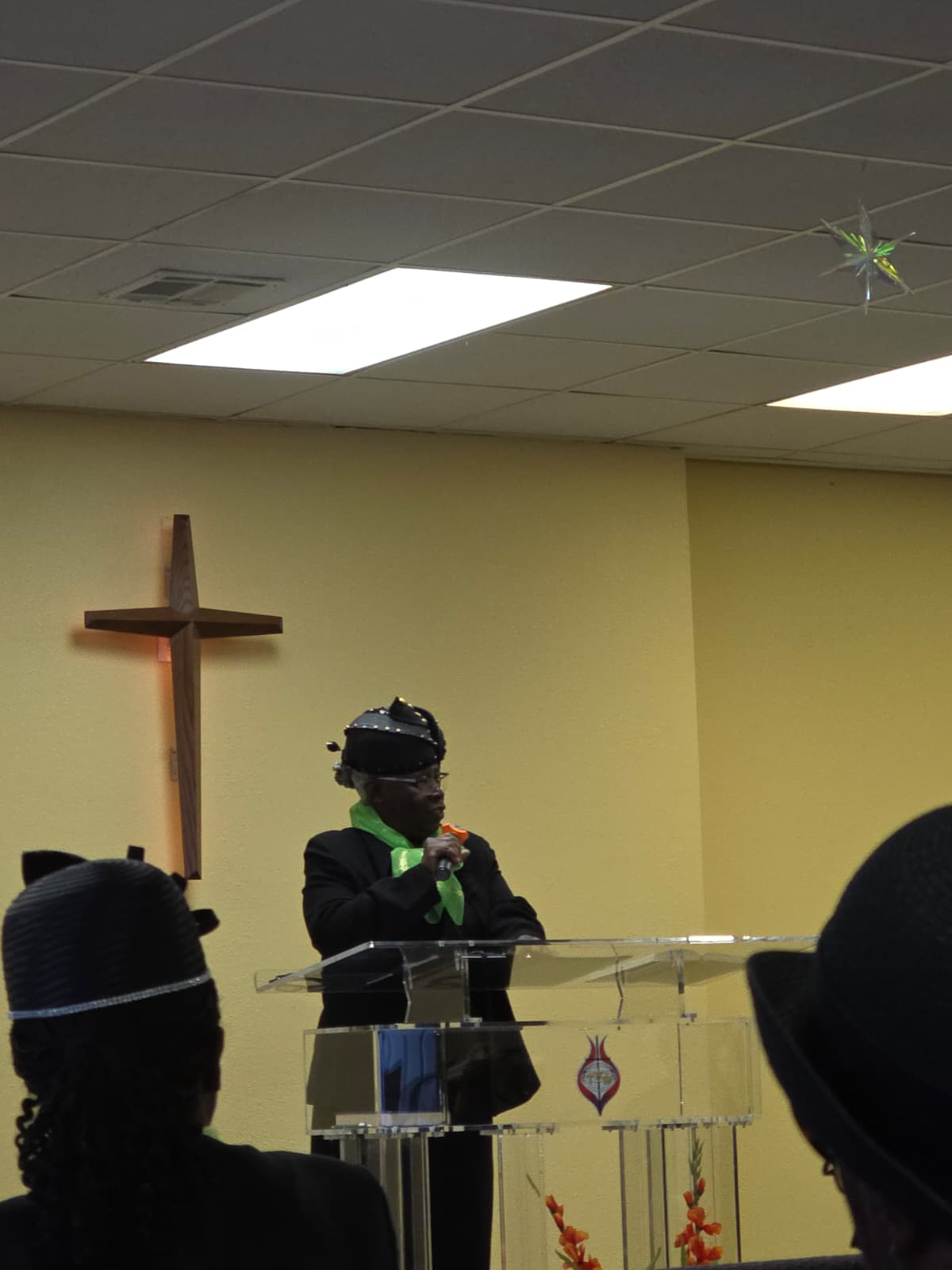 A speaker at a lectern beneath a cross
